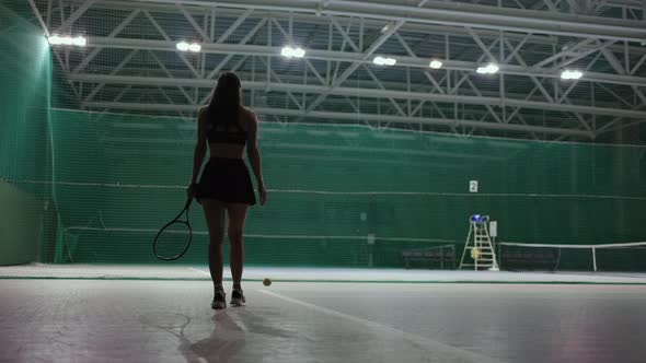 Sexy Woman on Indoor Tennis Court Rear View of Slender Lady in Sportswear Holding Tennis Racket