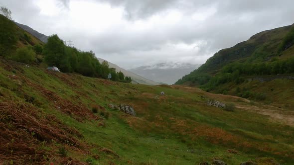 Cinematic drone shot of two highland sheep in valley with car passing by