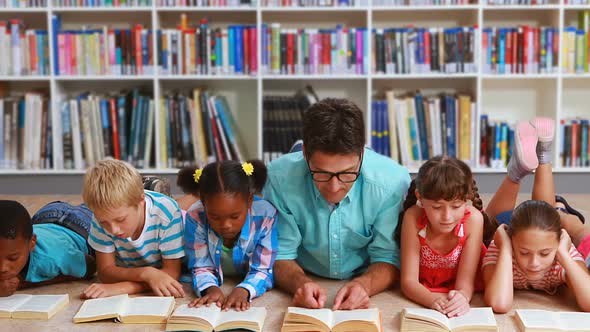 Teacher and Kids Lying on Floor Reading Book in Library