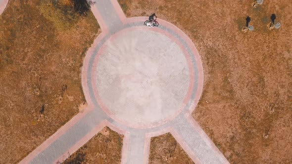 Top view of a bicycle woman riding a bicycle on a circular road in a city park.