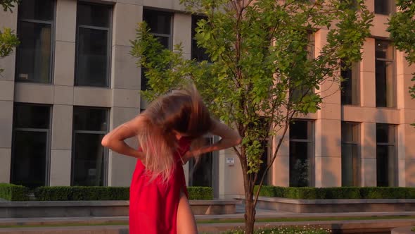 Beautiful Young Girl Dancing on the Street of a Modern Building of a Business Center in the Sunset