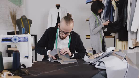 Bearded Tailor or Fashion Designer Sits on the Workplace at Studio 