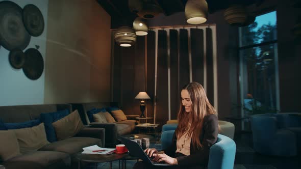 Cheerful Woman Working Laptop Computer in Hotel Lobby. Happy Business Woman