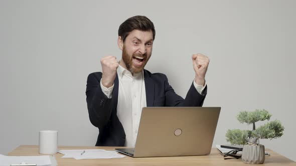 Happy male office employee in formal wear raising fists in triumph, celebrate good news