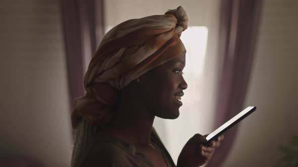 Black Woman Talking on Speakerphone Indoors