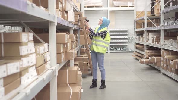 Muslim in a Hijab Holds Inventory with Barcode Scanner