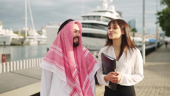 Businesswoman Talking with Arab Man on Embankment