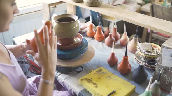 Female Potter Painting Clay Pot on Spinning Wheel Using Special Bulb Aplicator