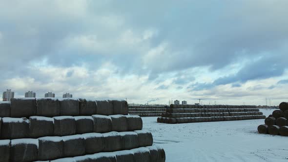 Flying over a snowy field. Straw bales are stacked. Traces of agricultural tillage under the snow.