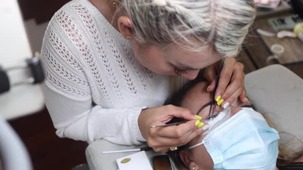 Beautician applying eyelashes on face of woman