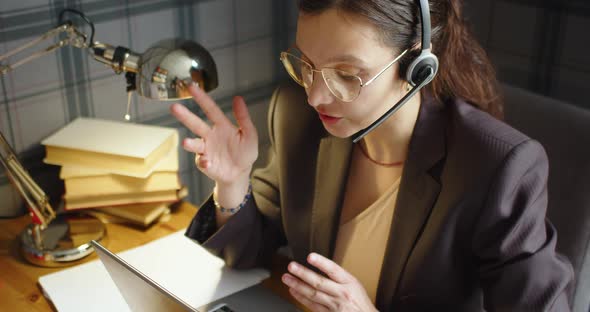 A Woman During an Online Video Call in a Library in Front of Laptop Monitor