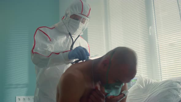 Doctor Examine Covid19 Patient Back with Stethoscope in Protective Suit Mask