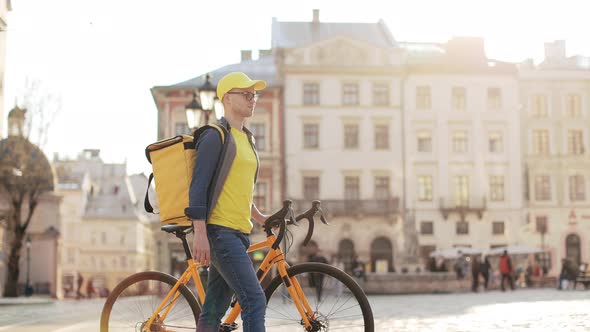 A Happy Delivery Man Who is Going and Holding a Bicycle