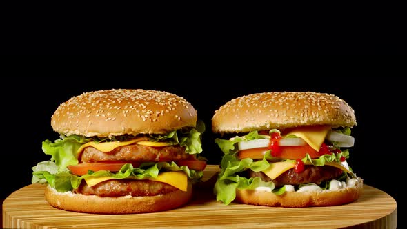 Two Craft Beef Burgers on Wooden Table Isolated on Dark Grayscale Background