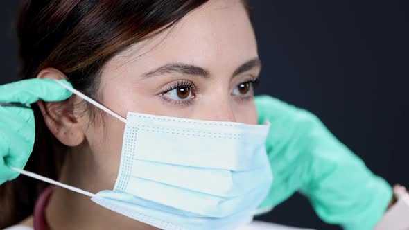 Young woman puts on and face mask wearing gloves