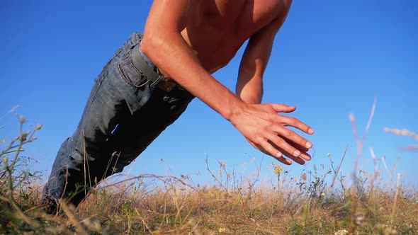 Young Athletic Man with a Bare Torso Performs Push-ups with Claps on Nature. Slow Motion