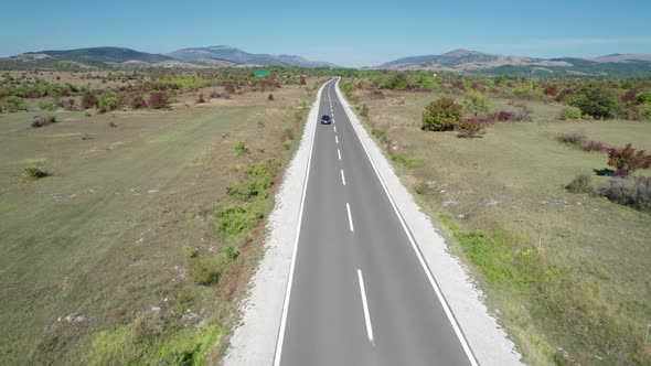 Aerial View Empty Asphalt Road on the Plateau Between Green Fields Highland Way