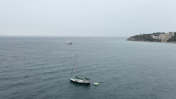 Sailboat And Catamaran Floating In The Ocean On A Chilly Overcast Day In Mallorca Spain