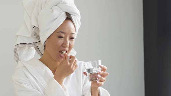 Attractive Japanese Woman After a Shower Takes Vitamins Medications She Is Dressed in a Bathrobe and