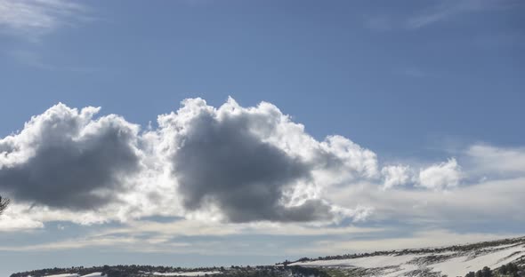 Time Lapse of Cloudscape Behind of the Mountains Top. Snow, Rocks, Cliffs and Deep Blue Sky