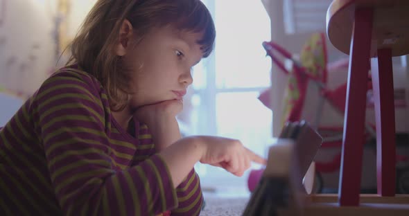 Girl is Lying on the Floor in Her Room and Looking Something on Tablet