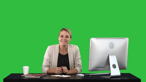 Excited business woman talking on camera sitting at desk