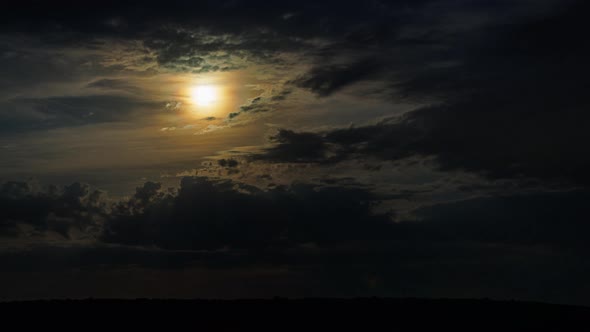 Moon Behind Clouds Above Horizon at Dark Night Timelapse