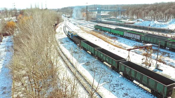 A freight train with containers moves along the rails in the direction of the city in a winter day.