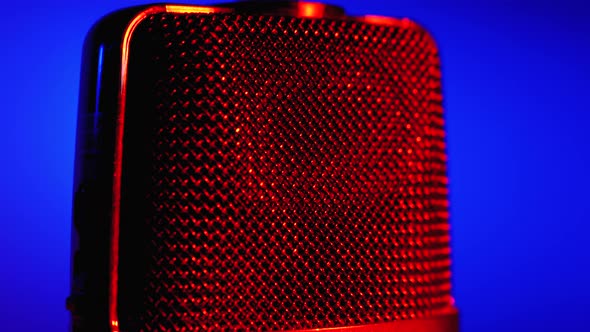 Condenser Microphone Rotates with Blue and Red Backlight. Professional Audio Recorder Close-up