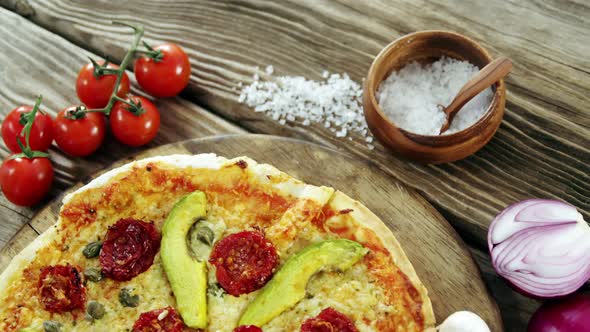 Italian pizza on wooden table with vegetables and spices