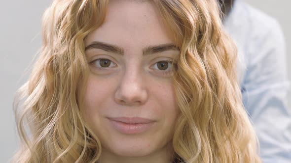 Giving the Blonde Hair Shape and Volume. Styling Curls on the Head of a Young Girl.