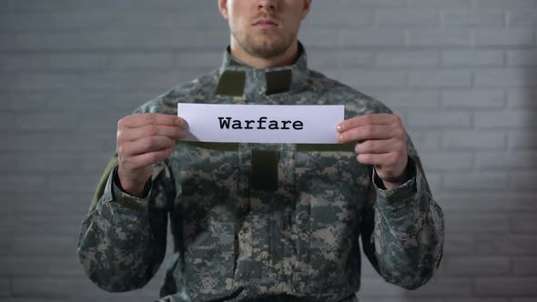 Warfare Word Written on Sign in Hands of Male Soldier, Military Conflict