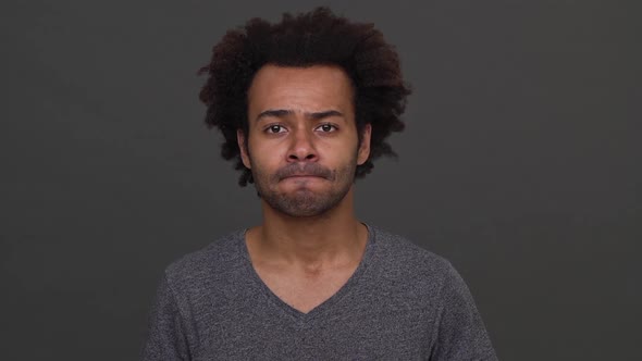 Darkskinned Man with Afro Haircut Standing with Apologetic Glance and Nodding Negatively Isolated