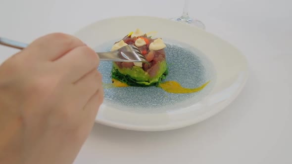 Close Up of a Hand with a Fork Eating a Tartar with a Raw Tuna Fish