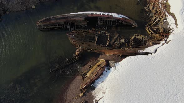 Aerial Top View of Old Wrecked Fishing Ships Drowned at the Sea Shore in Snowy Winter Season