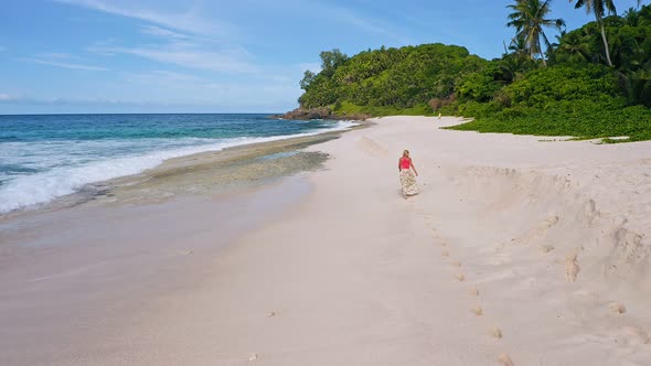 Camera Follows Young Woman As She Walks on the Paradise Anse Bazarca Beach