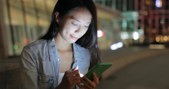 Young woman looking at mobile phone at night