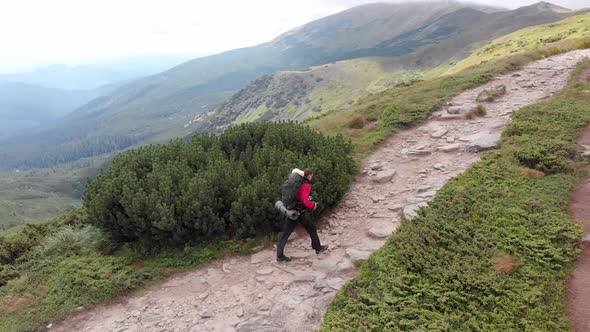 Aerial View of a Traveler with a Backpack Climbing Along Mountain Slope