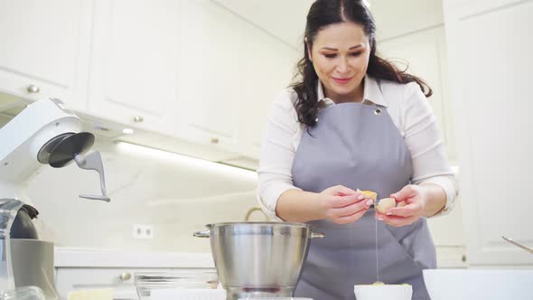 A Woman Breaks an Egg and Separates Yolks From Proteins