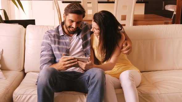 Couple relaxing on sofa and using digital tablet