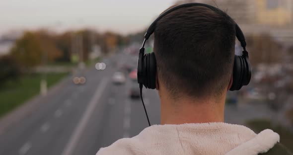 Rear View of Man Listening a Music in Headphones on City Bridge