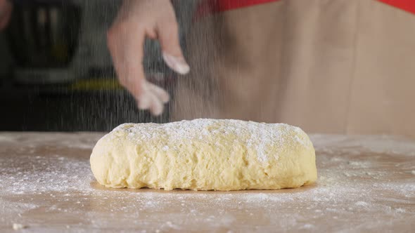 Pastry Chef Sprinkles Dough with Flour on the Table