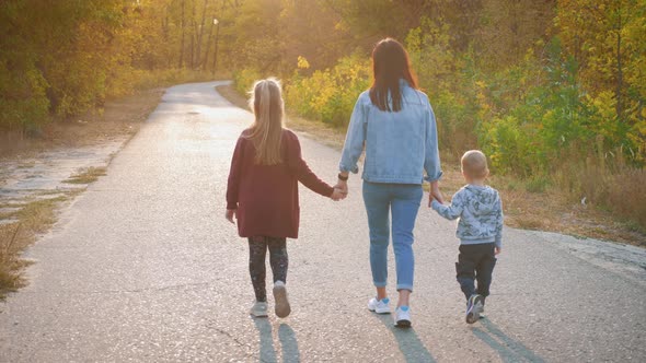 Mother and Two Children Walking in the Park and Enjoying the Beautiful Autumn Nature. Happy Family