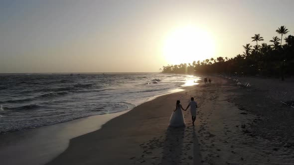 Drone Footage of the Beautiful Sunset at the Tropical Beach with Couple Walking
