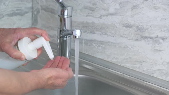 Man Washes His Hands with Soap Under the Streem at Home