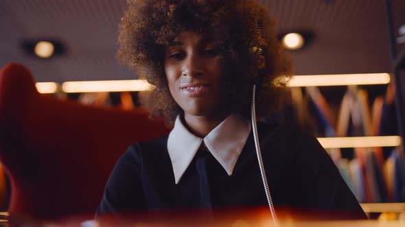 Woman With Afro Listening To Record Player With Headphones