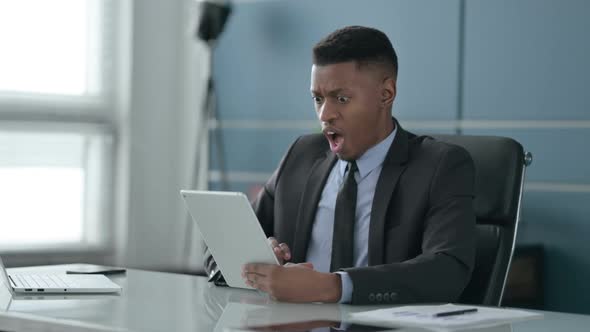 African Businessman Reacting to Loss on Tablet in Office