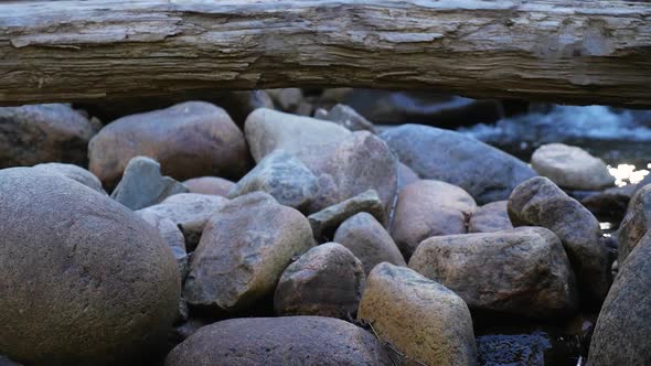 Rocks With Log On Top And Small Rapids Behind