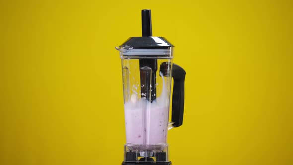 Blender Shaking Mixing Milk with Berries in Slow Motion at Yellow Background