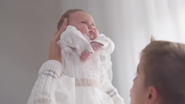 Live Camera Follows Charming Infant in Hands of Teenage Boy Raising Child in Slow Motion